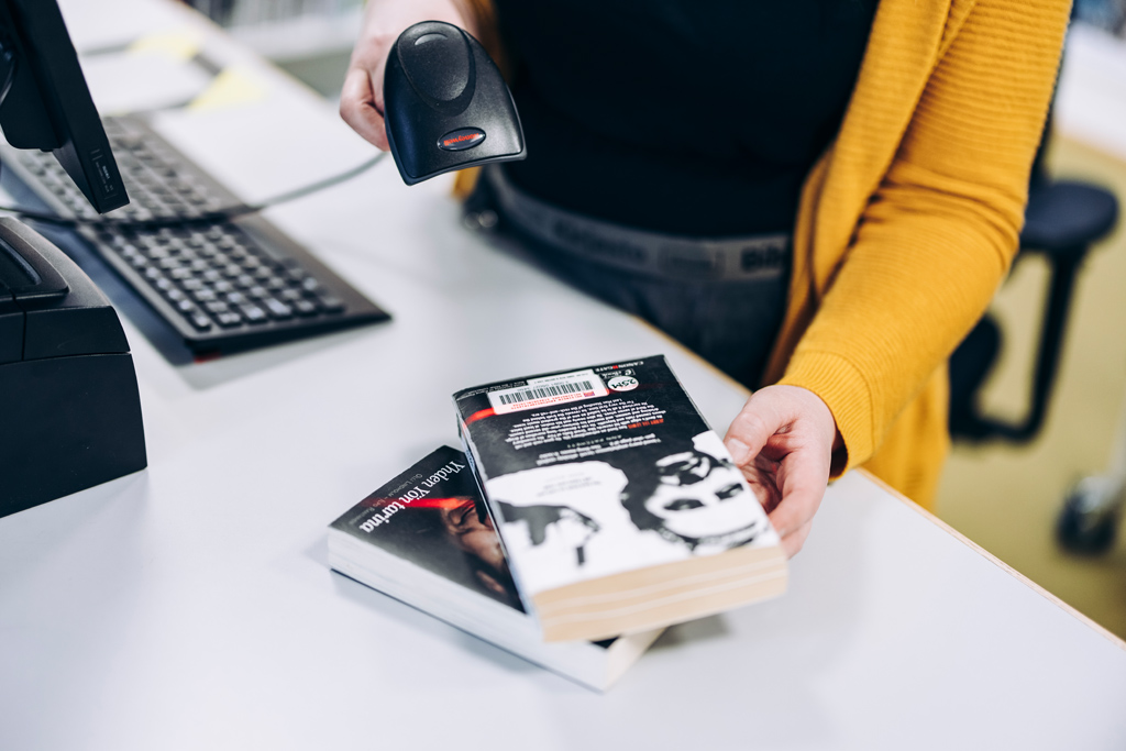 Kirjastovirkailija lukee viivakoodia lainattavasta teoksesta.